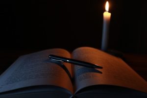 A book dimly lit by a candle suggesting secret knowledge